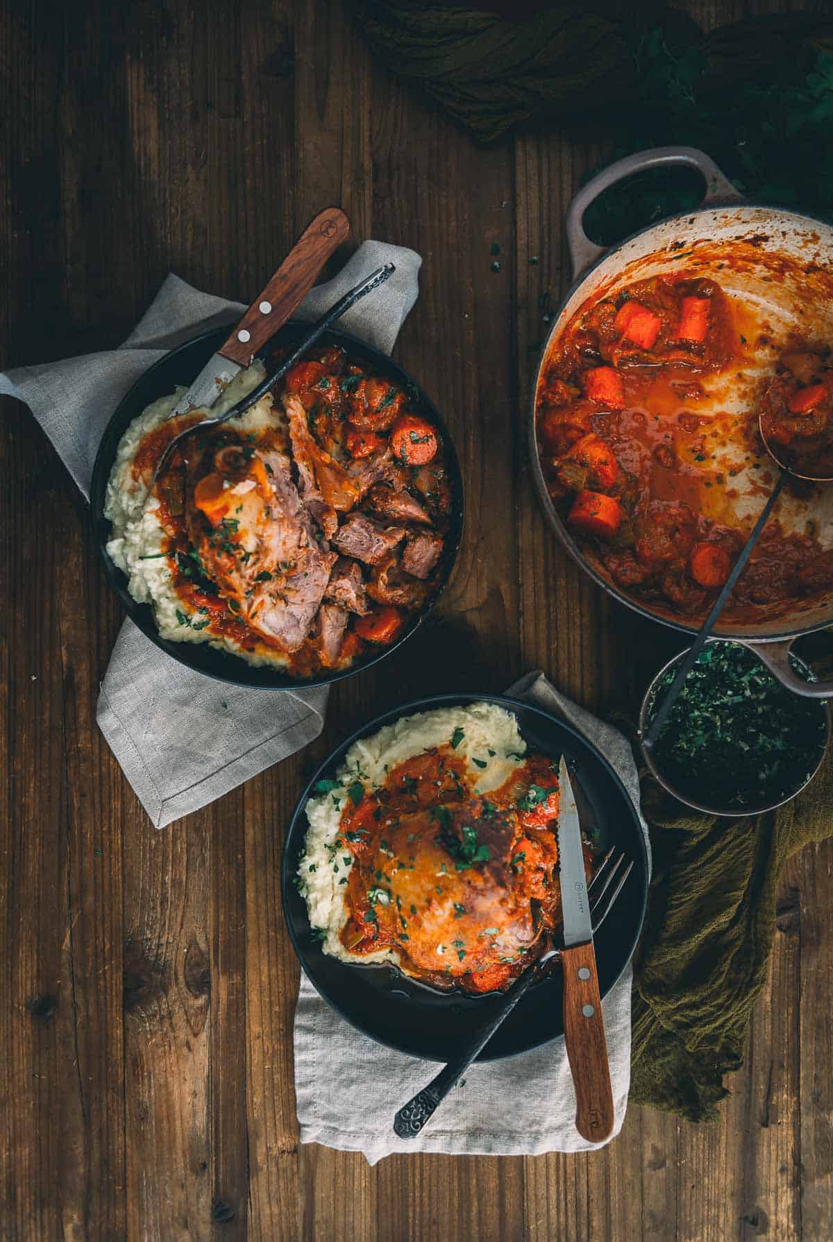Platters of braised pork shanks in a rich sauce over mashed potatoes.