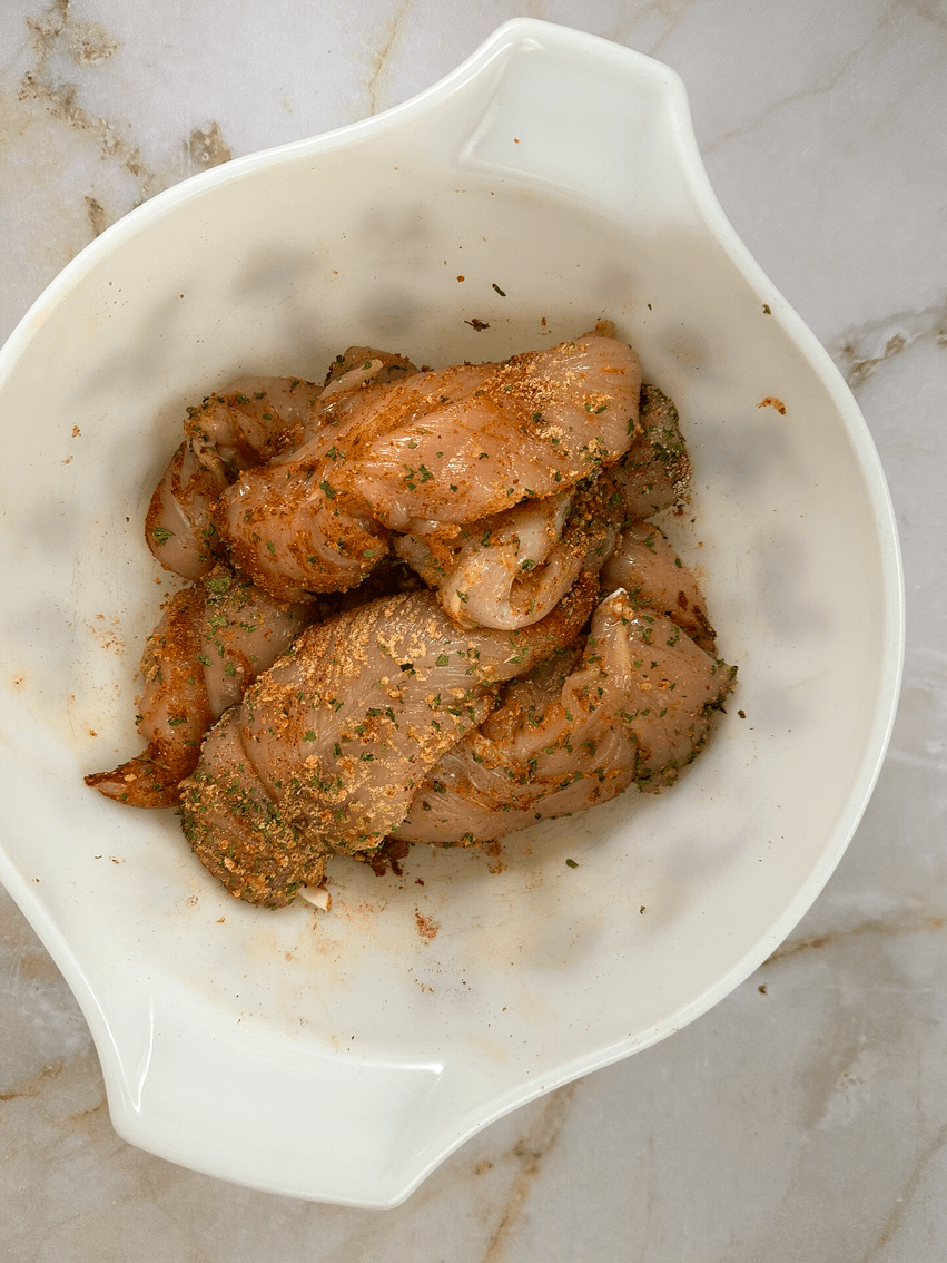 Seasoned chicken tenders in a bowl.