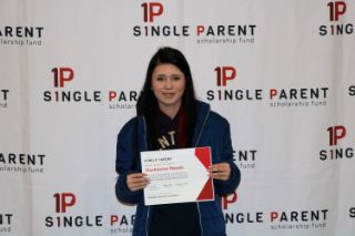 A woman stands with her certificate