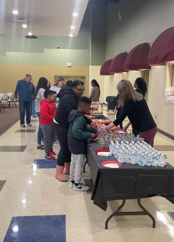 Families get food at a breakfast buffet