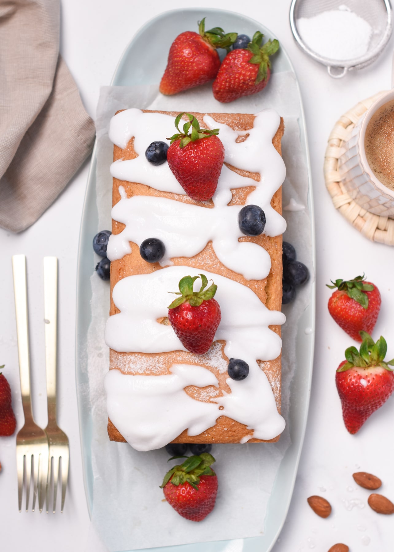 Almond Flour Pound Cake decorated with frosting and fresh strawberries.