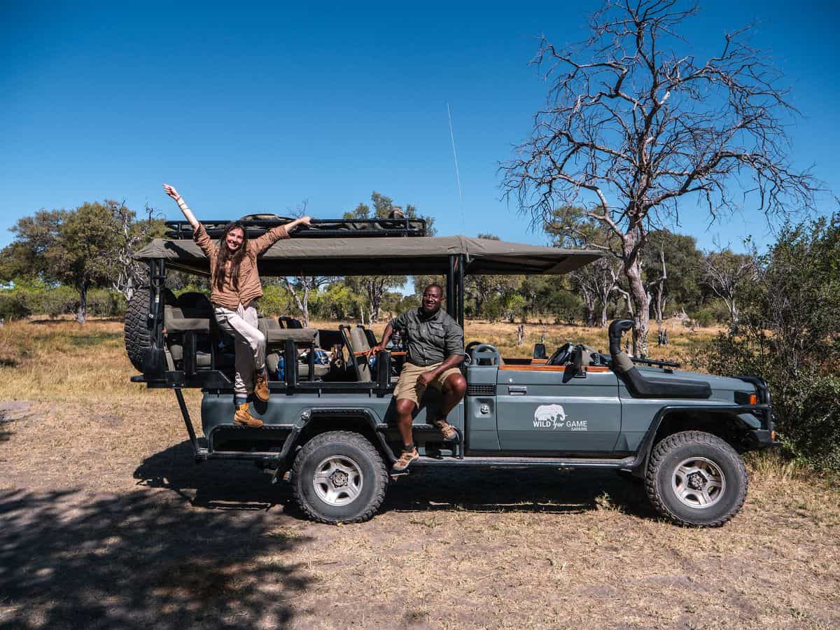 A solo female traveler on safari in Tanzania, standing on a safari vehicle with a guide amidst the scenic savannah landscape.