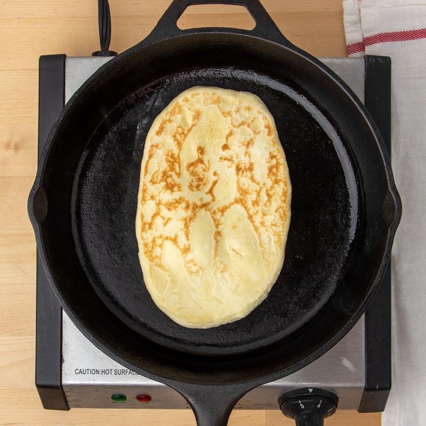 same dough flipped onto opposite side in skillet, with light brown markings on top