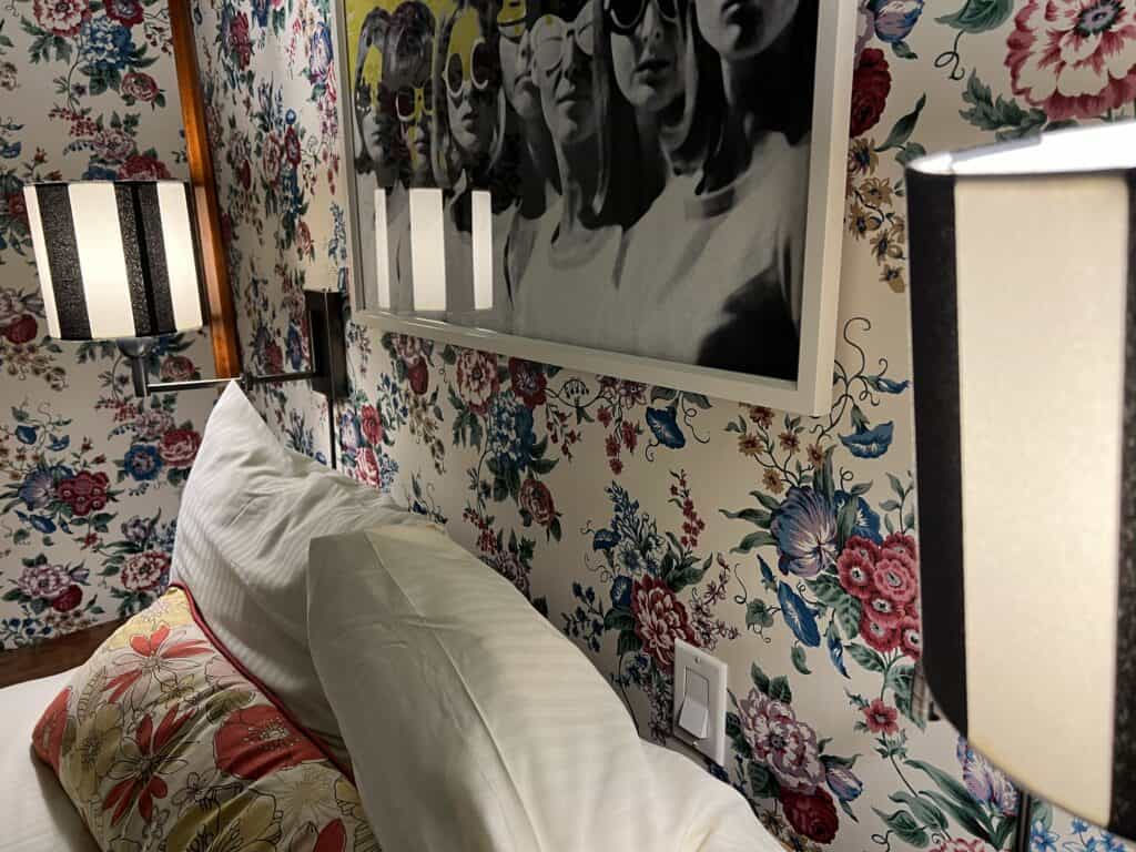 Charming British Hotel in San Francisco: My Stay at White Swan Inn 6 Close-up of a bed with decorative pillows hiding the elusive fireplace switch, with a note directing guests to the wall control.