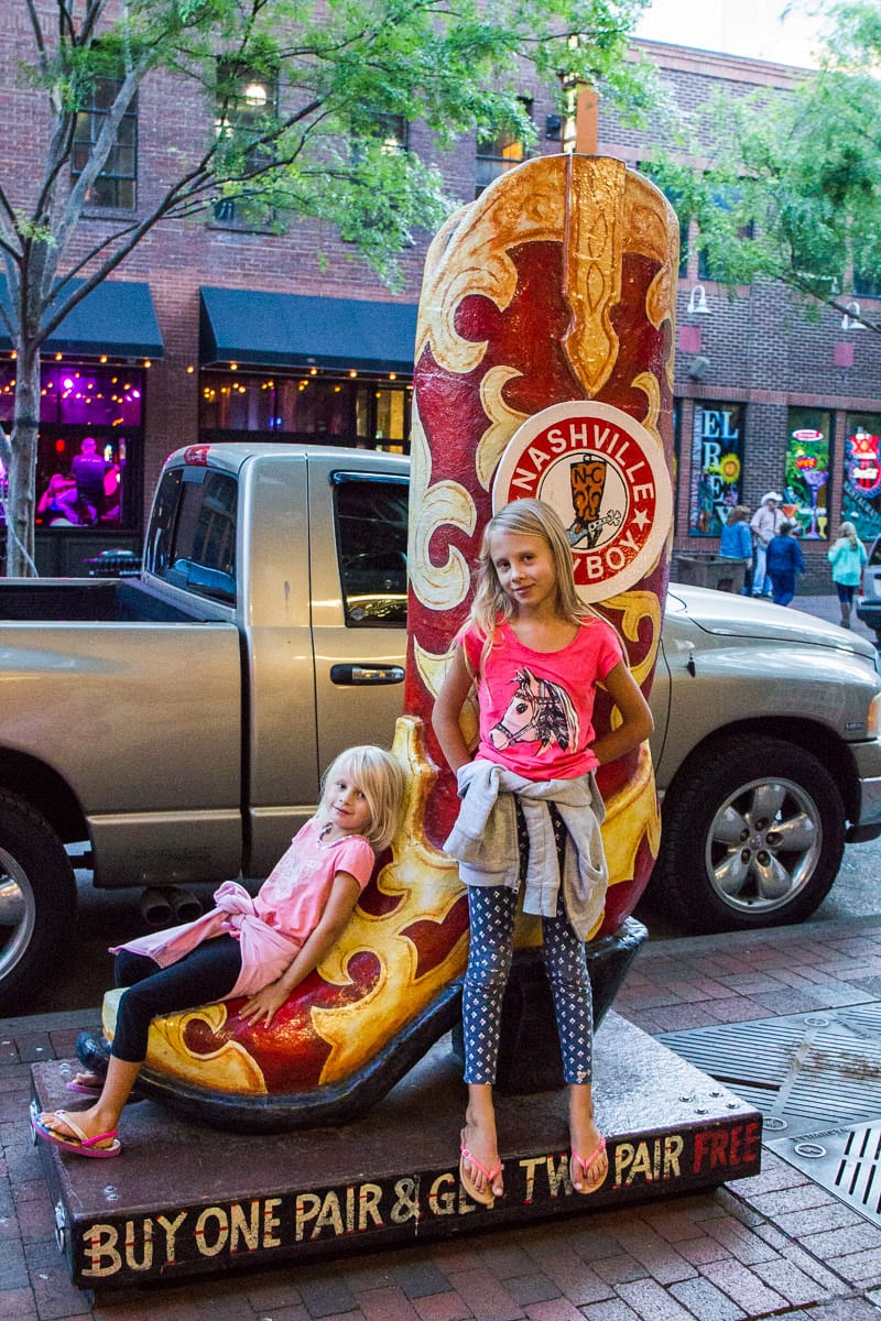 girls standing beside giant cowgirl boot in downtown Nashville