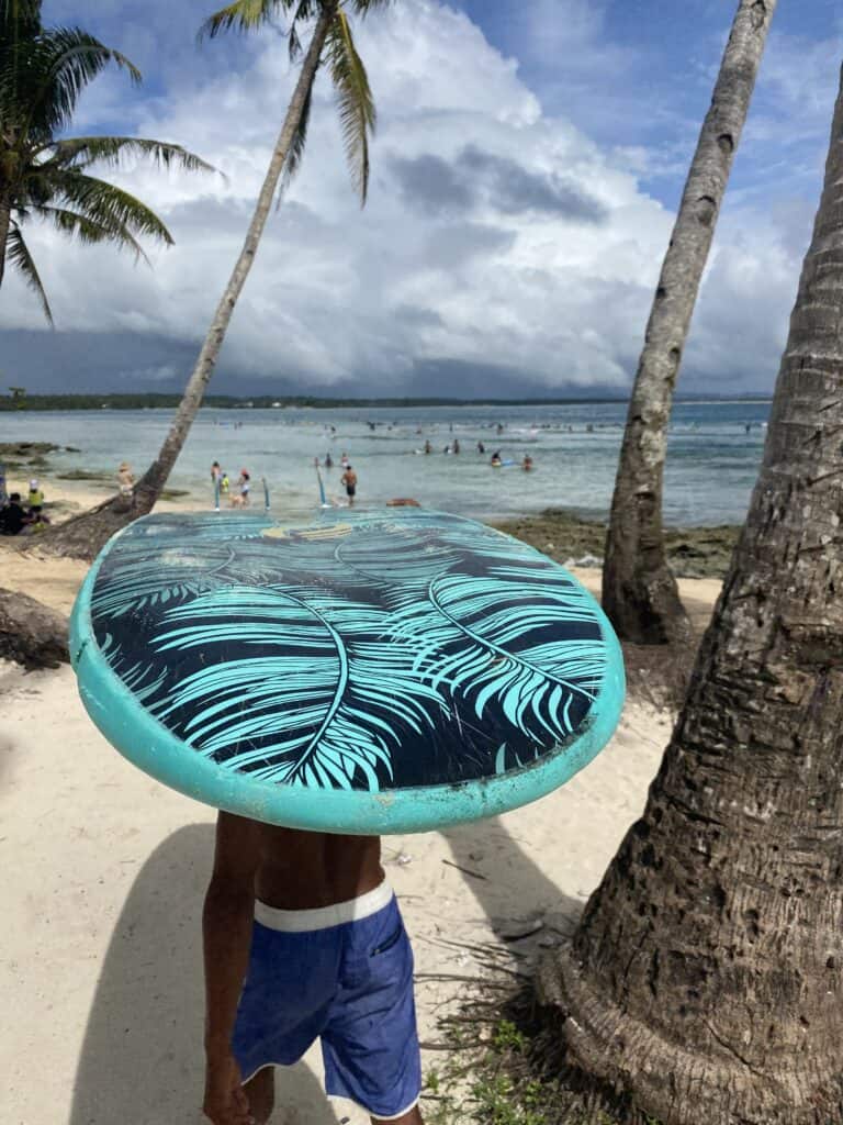 Carrying surfboard to the beach in Siargao