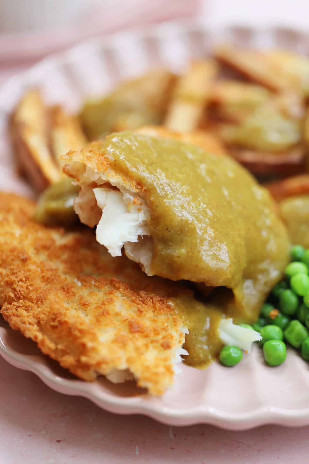 A portion of gluten free fish and chips with homemade curry sauce.