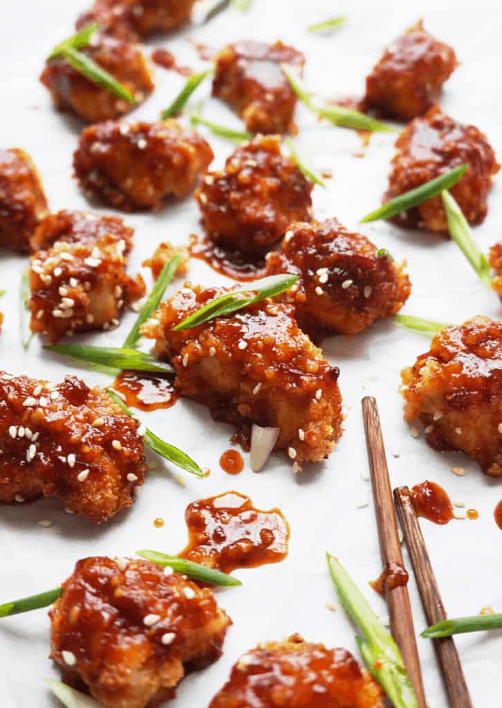 Chicken nuggets coated in sauce and garnished with green onion slices.