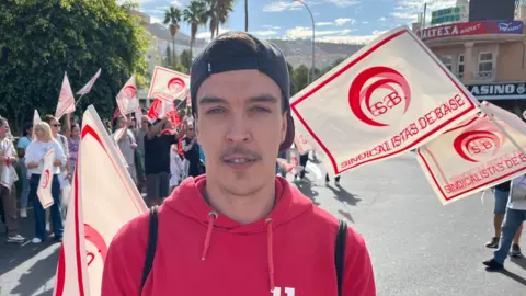 Emma Davies/BBC Fernando is a young Spanish man wearing a red hoodie and black cap on backwards
