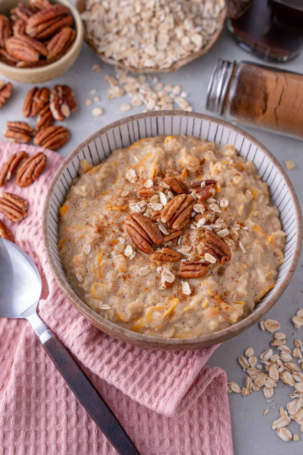 A bowl of carrot cake porridge topped with pecan nuts.