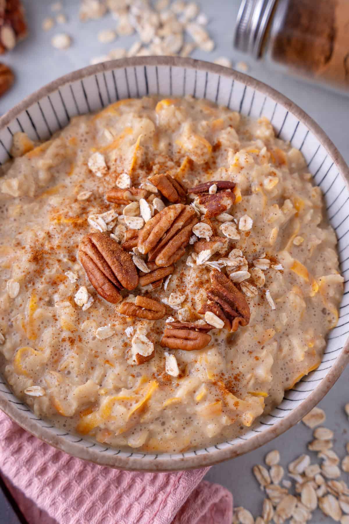 A bowl of carrot cake porridge topped with pecan nuts.