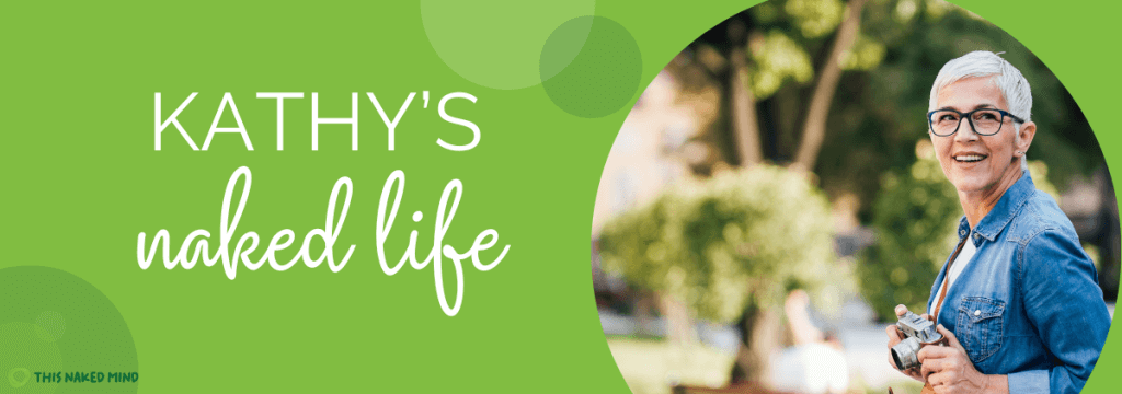 why am I drinking more as I get older - Kathy's Naked Life - older caucasian woman in glasses with a camera around her neck smiling - (c) 2025 This Naked Mind