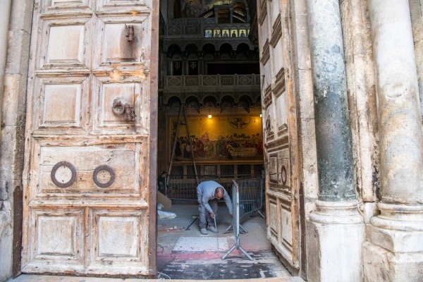 A worker at the threshold of the Basilica of the Holy Sepulcher in Jerusalem in early April 2025. Ahead of the Easter celebrations, the construction site was closed and a temporary pavement was laid to allow the liturgies to take place. Credit: Marinella Bandini