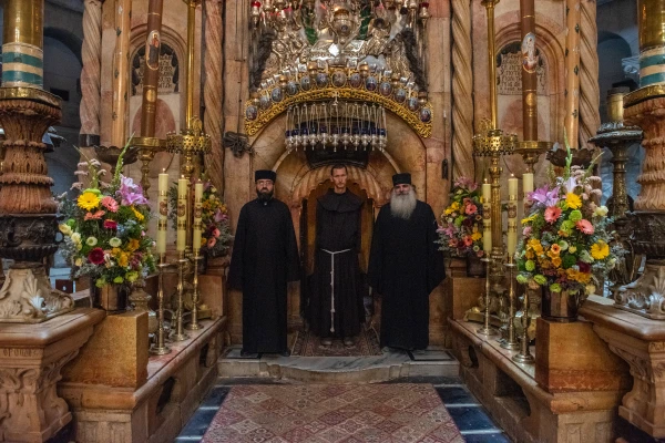 The sacristans of the three communities that guard the Basilica of the Holy Sepulcher in Jerusalem — Greek Orthodox, Latin Catholics, and Armenians — stand in front of the door of the edicule that contains the venerated tomb. Credit: Marinella Bandini