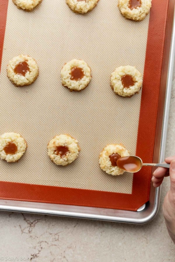 spooning caramel into macaroon thumbprints.