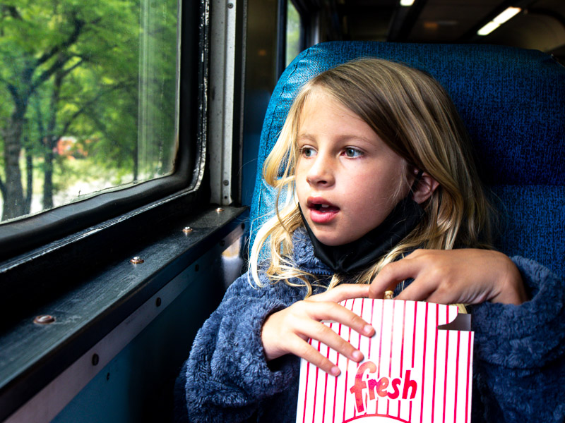 girl eating popcorn looking out train window
