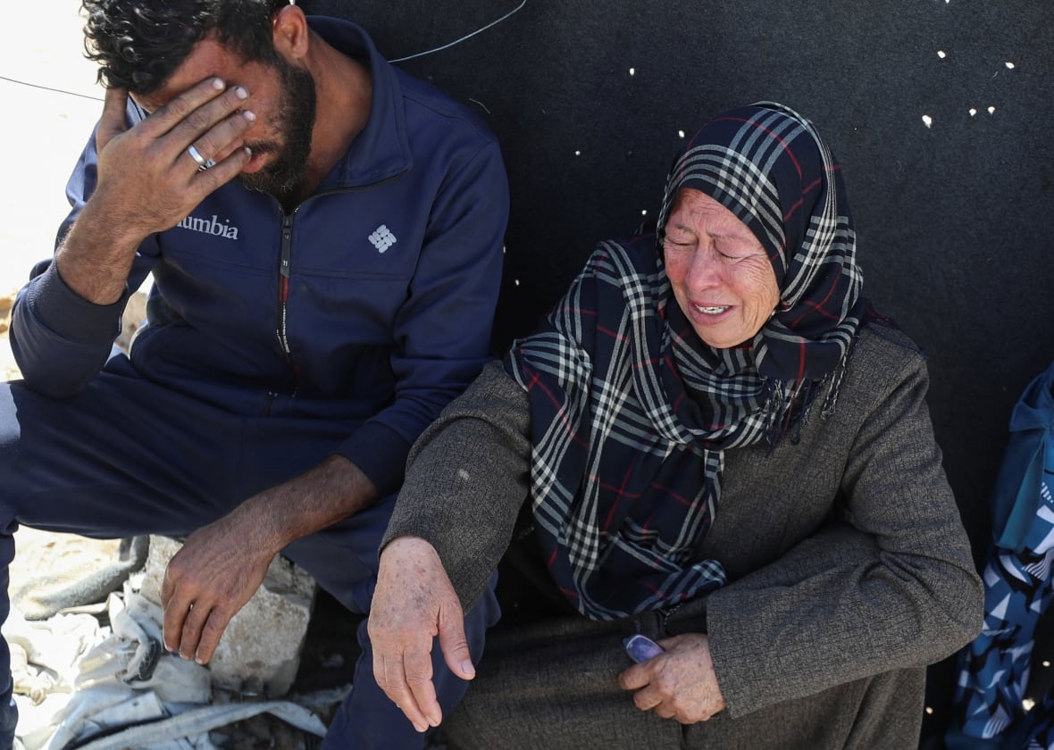 An elderly woman cries as she sits next to a man.