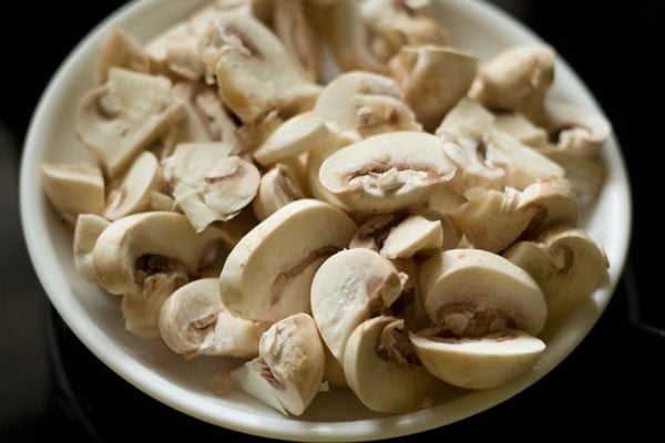 chopped button mushroom in a white plate for making mushroom curry.
