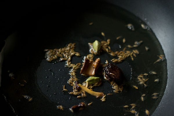 sautéing spices in hot oil in pan for making mushroom curry.