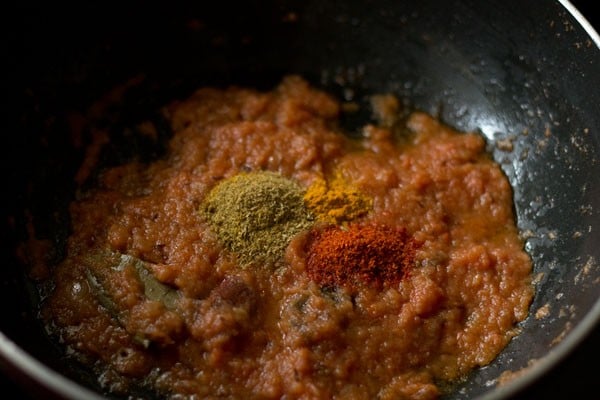 spice powders added to onion-tomato masala in pan.