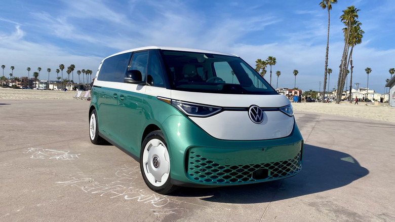 front three quarters of a green and white VW ID Buzz in front of palm trees