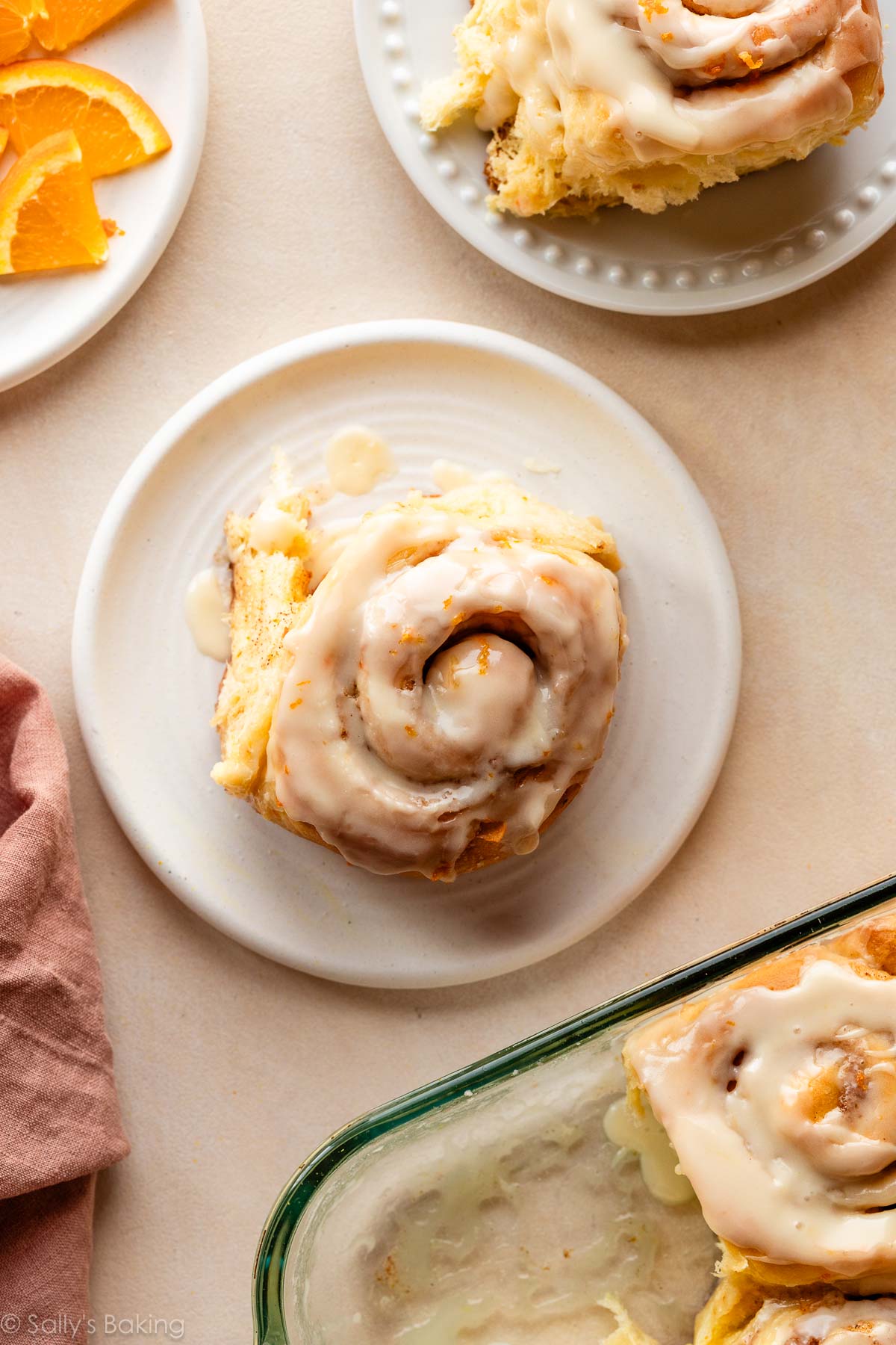orange sweet cinnamon roll with icing on white plate.