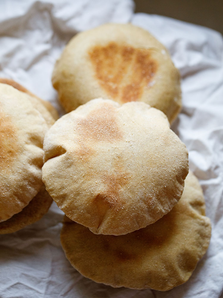 top view of puffed up pita bread placed on white cotton napkin. 