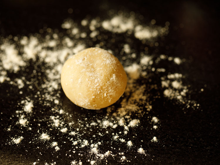ball of dough placed on working surface with flour sprinkled all over for pita bread recipe. 