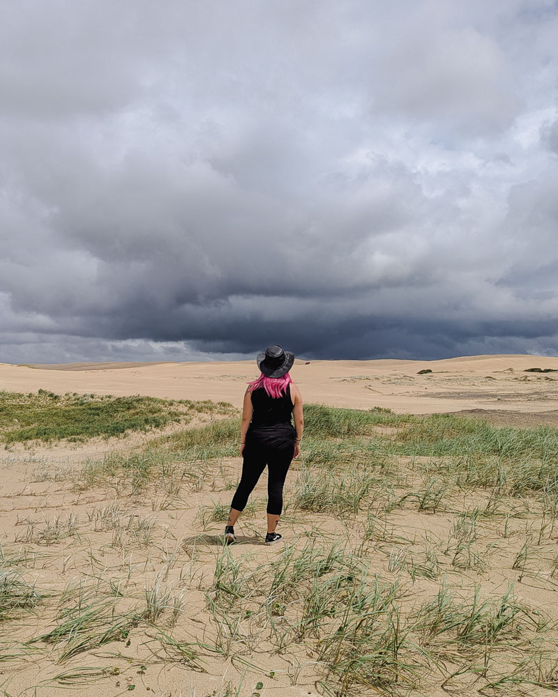 Milly standing on sand dunes looking up at the dark sky