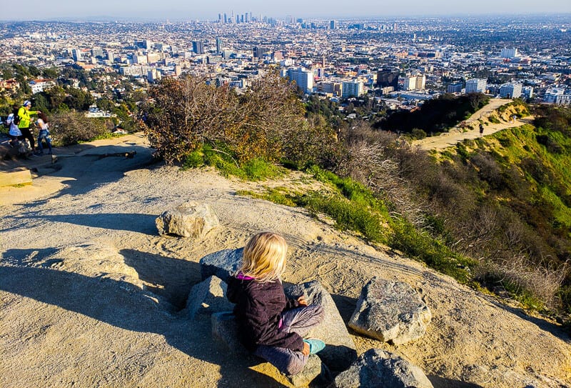 girl on rock in Runyon Canyon Hike, looking at LA skyline views