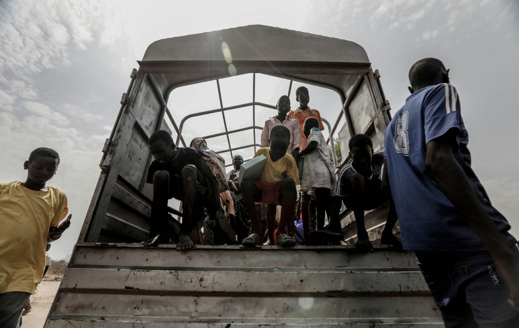 Children disembarking from the back of a truck