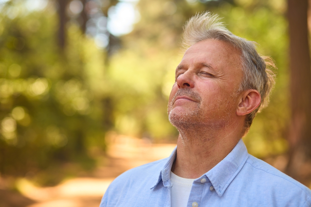 Peaceful,Senior,Man,Relaxing,Standing,Amongst,Nature,In,Forest,Surrounded