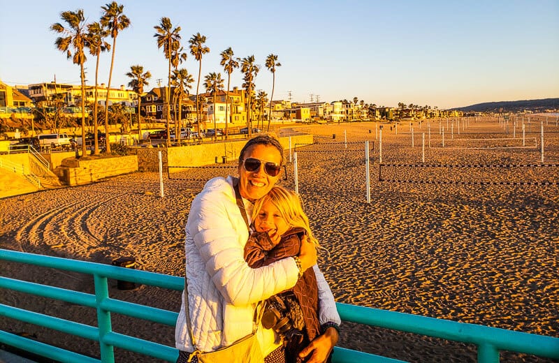 mother and daughter hugging on manhattan beach pier