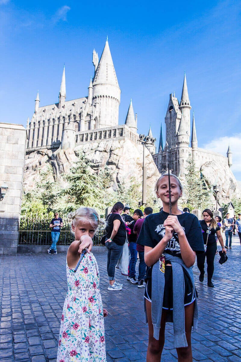 two girls with wands at hogwarts castle in universal studios