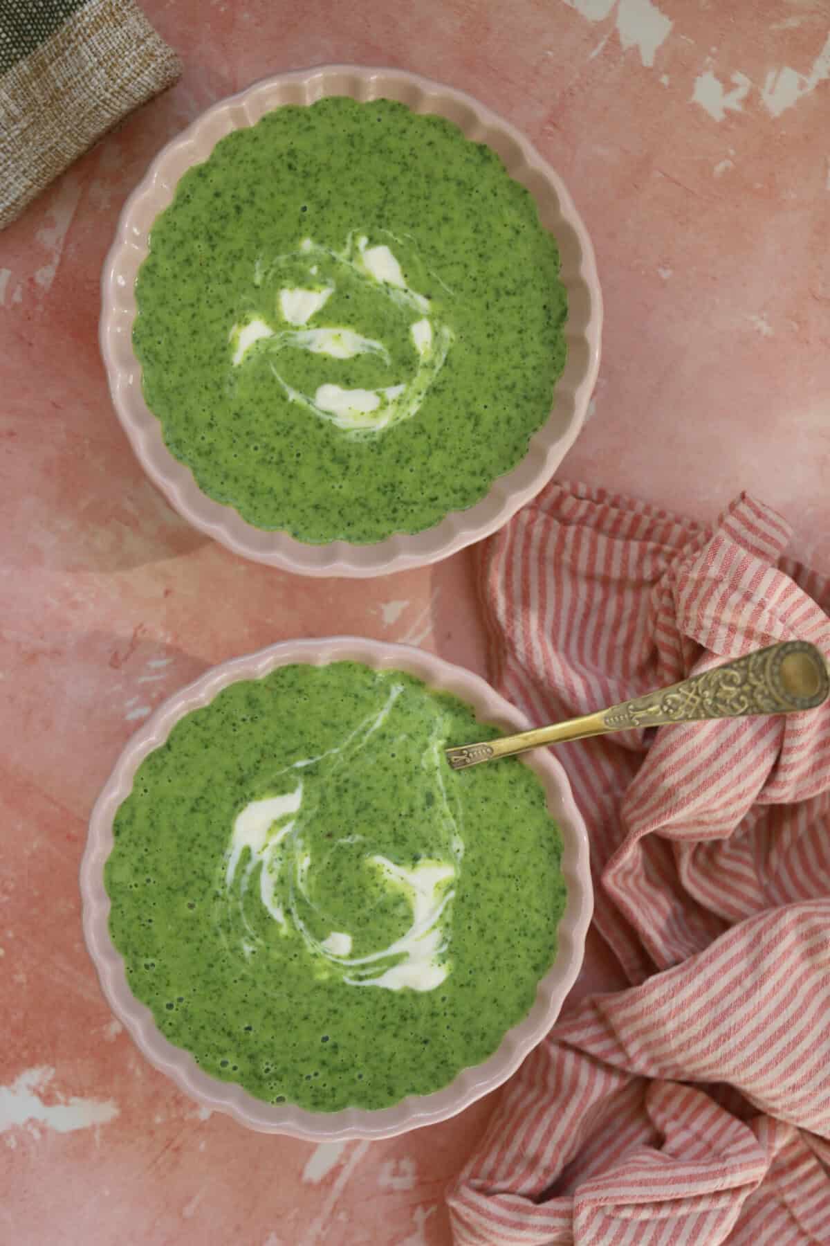Two bowls of gluten free watercress soup on a pink backdrop.
