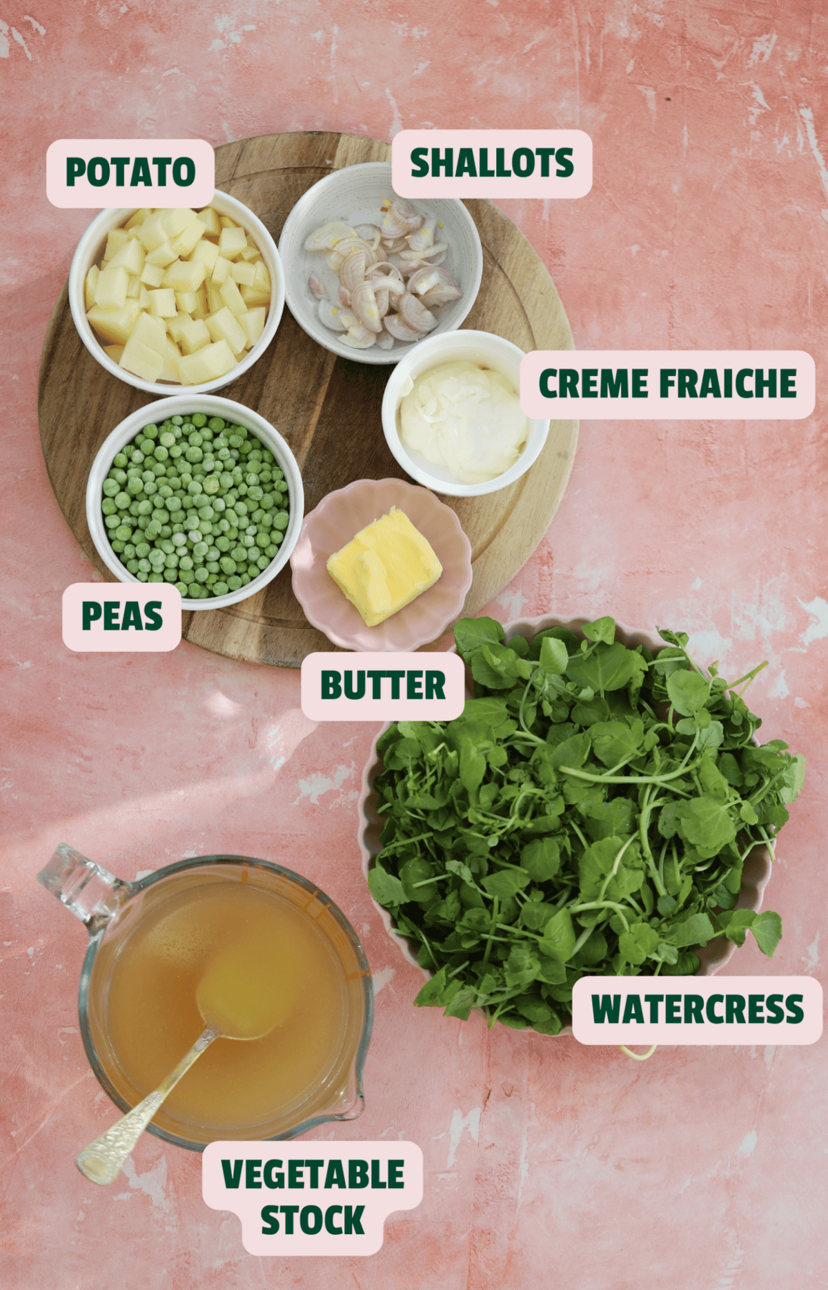 Ingredients for watercress soup on a pink backdrop with text labels.