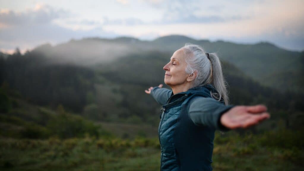 woman outdoors arms outstretched.
