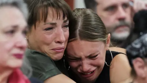 Reuters Dylan Mortensen cries into the shoulder of another woman who is also crying