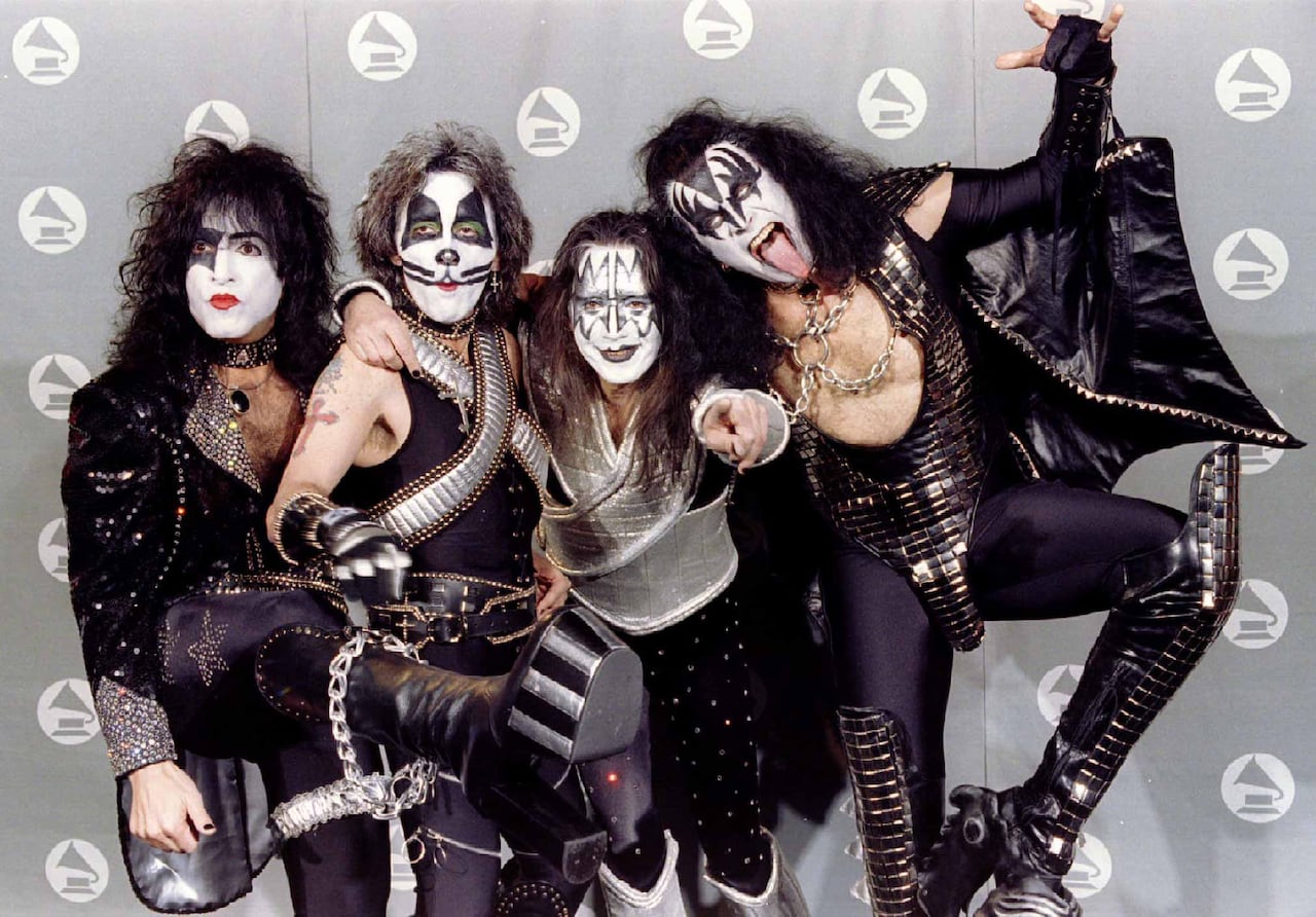 Four men in black-and-silver costumers with black-and-white face makeup.