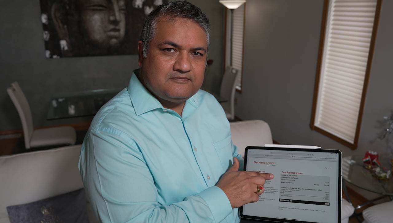 Man in blue shirt holding up his laptop computer and pointing at the screen