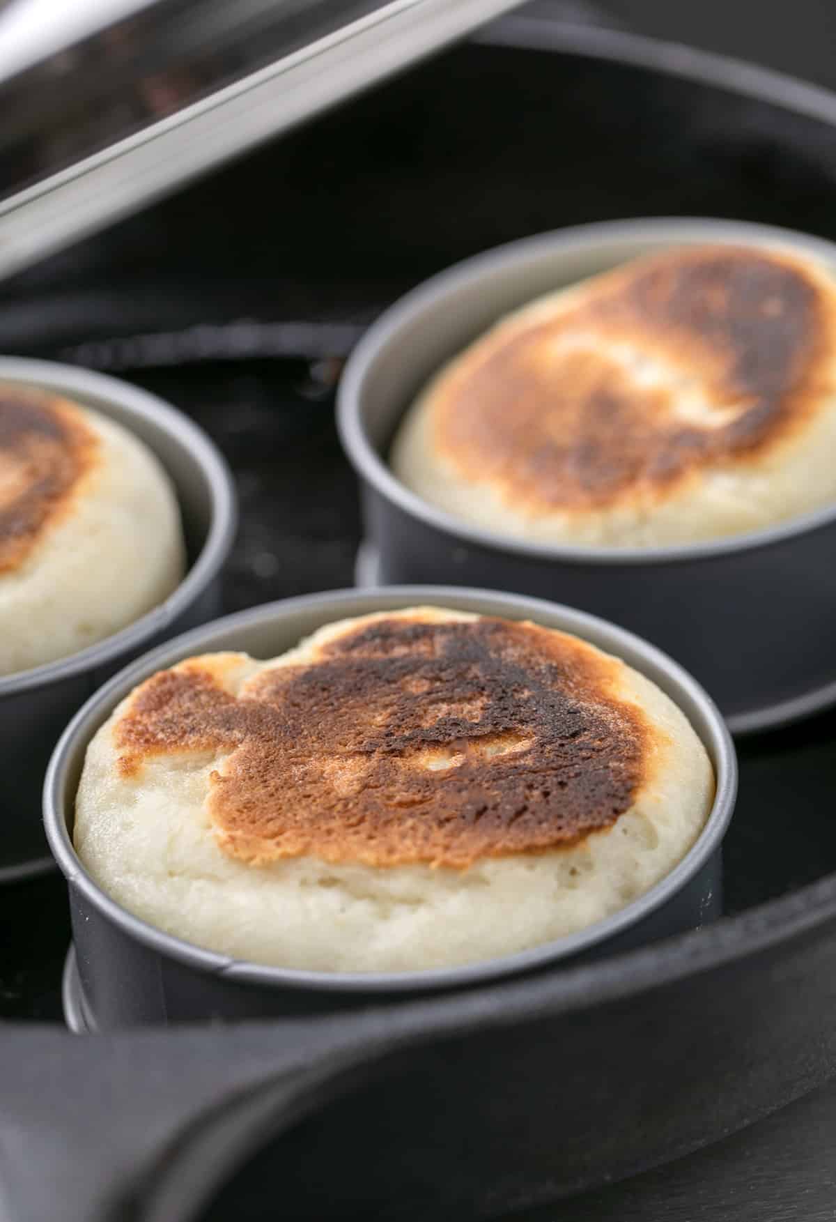 3 English muffins in rings in a round cast iron skillet