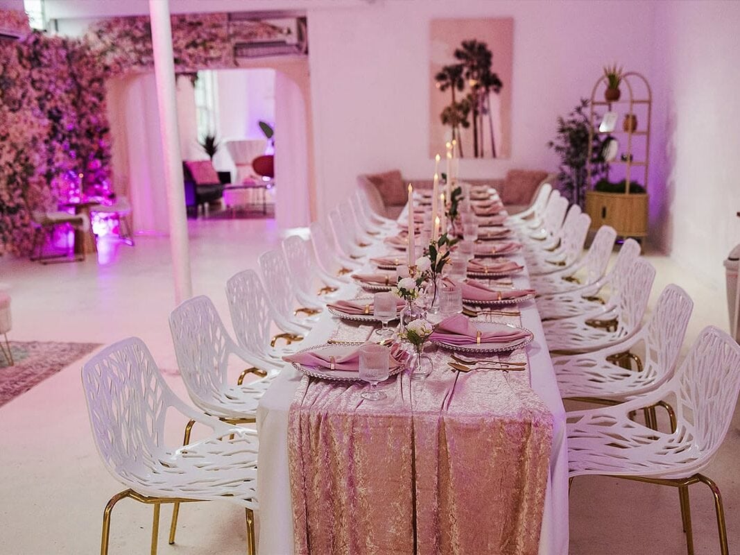 Pink glowy interior with long table and chairs set up by Chicago wedding planner