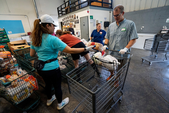 Volunteers load groceries into carts for families arriving to pick up online orders at The Pantry by Feeding Hawaii Together, Monday, Nov. 10, 2025, in Honolulu. (AP Photo/Mengshin Lin)