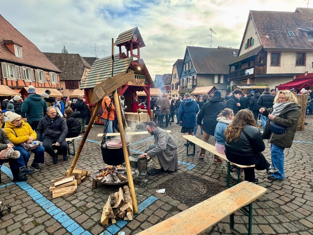 Meats roasting over a fire in the middle of a medieval square in France.