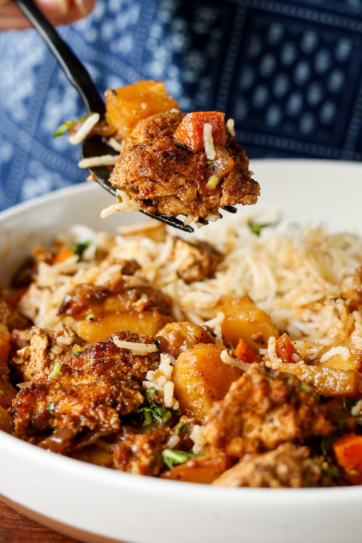 fork taking a bite of braised tofu and veggies with rice and herb sauce