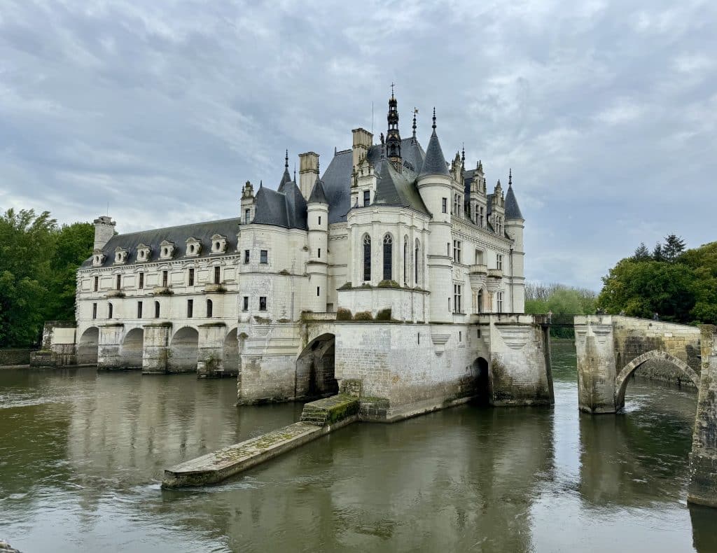 A White Castle perched on a river with a bridge leading across it.