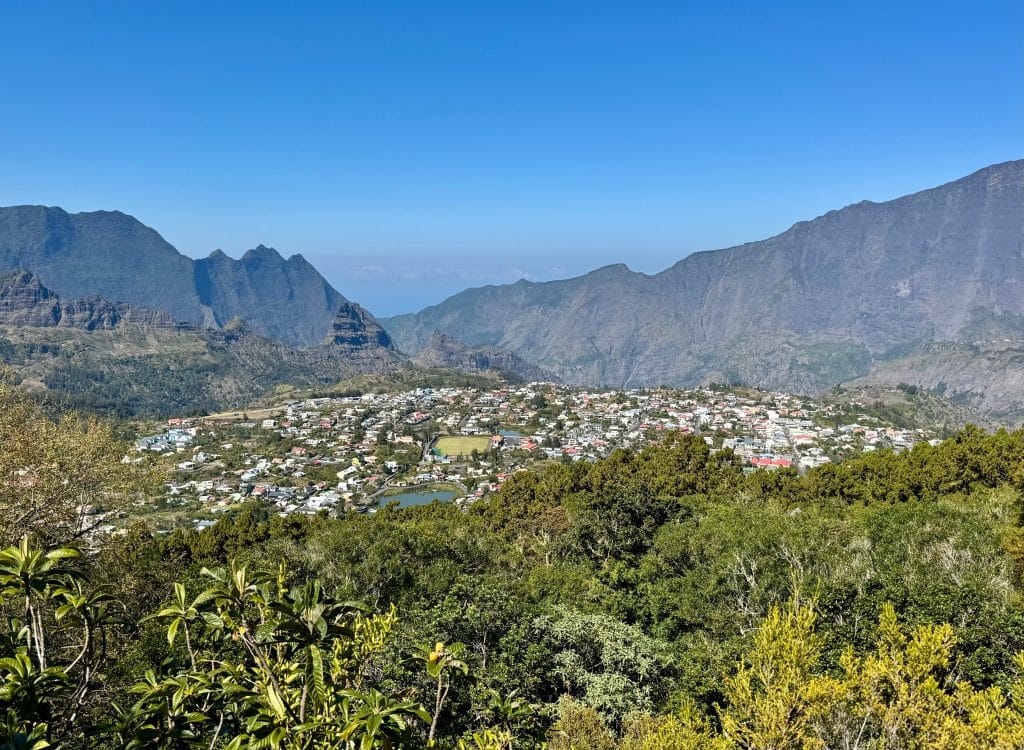 A view from above of a tiny village surrounded by volcanic mountains on all sides.