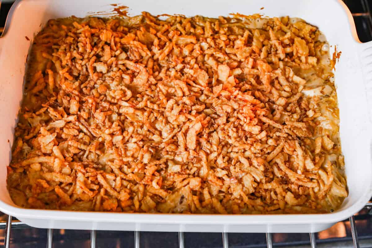 Creamy, cheesy, and packed with shredded chicken, this French onion chicken casserole is comfort food at its best! Inspired by French onion soup and dip, it’s topped with crispy fried onions for a crunchy finish. Picture of french onion chicken casserole in the oven with crispy onions added to the top.