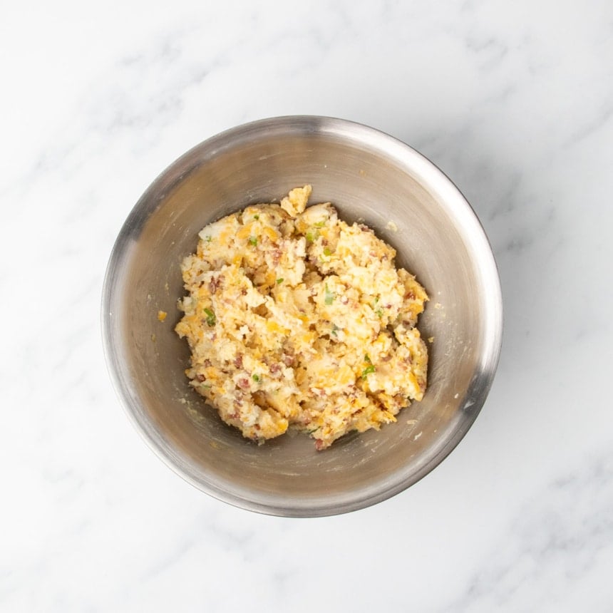 Mashed potato mixture fully combined into a soft dough in a stainless steel bowl.