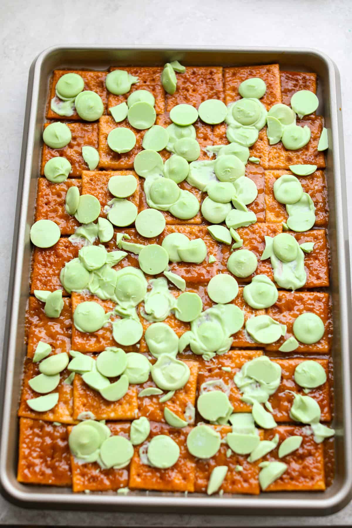 If you want a quick, crunchy treat with a bit of holiday mischief, this Grinch Christmas Crack is it. Sweet, salty, and totally addictive. My classic Christmas Crack is always a hit, but this version brings all the Grinchy fun! Light green candy melts spread over the hot toffee on the crackers.